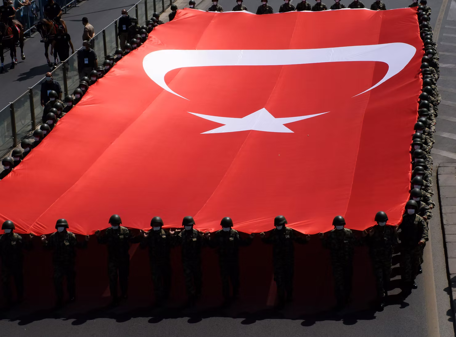 Bir tören yürüyüşünde taşınan büyük Türk bayrağı